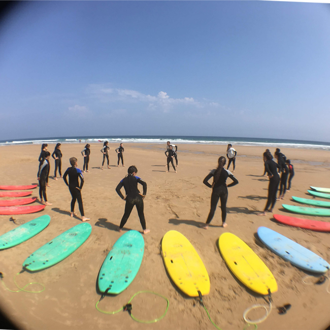 Estudiantes de Escuela Surf Berria remando en el mar, aprendiendo a buscar olas