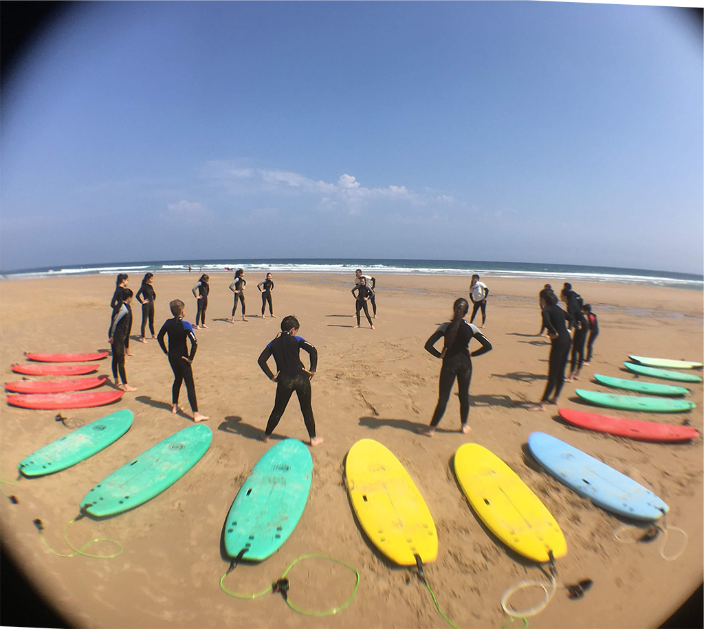 Estudiantes de Escuela Surf Berria remando en el mar, aprendiendo a buscar olas